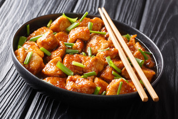 Stir-frying chicken fillet in sweet sauce with green onions close-up in a plate. horizontal