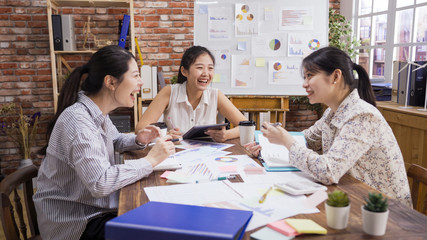 Fototapeta premium Group of contemporary business female people working in meeting room. three asian chinese lady coworkers laughing cheerful during project discussion in vintage bright office. woman sharing ideas.