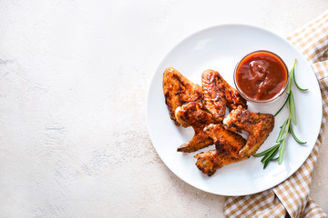 Plate with tasty fried chicken wings and barbecue sauce on white table
