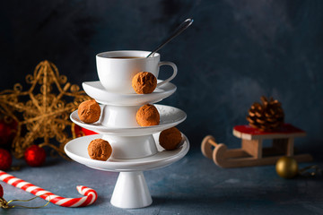 Creative concept with white dishes Christmas tree shape pyramid with cup of tea on top decorated with sweet chocolate truffles on dark background. Wallpaper, postcard about Xmas, New Year. Horizontal