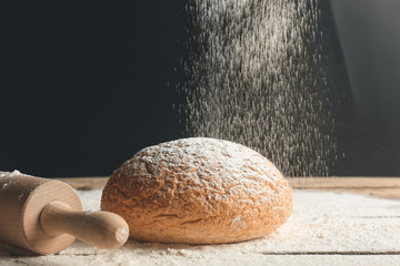 Fresh bread with sprinkling flour on table