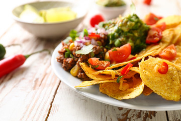 Plate with tasty chili con carne and nachos on table, closeup