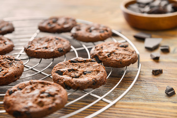 Cooling rack with tasty chocolate chip cookies on wooden table