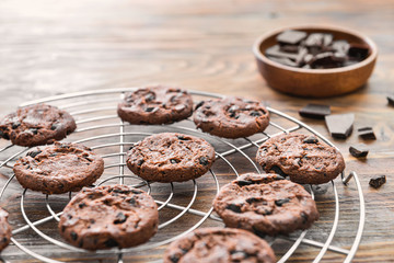 Cooling rack with tasty chocolate chip cookies on wooden table
