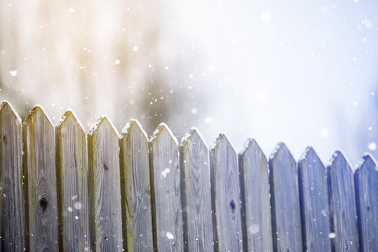 Wooden village fence in winter and snowfall
