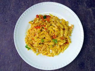 some yellow eatable food put in a white plate on stone background