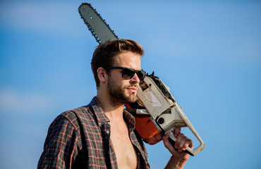 Get stylish haircut. Barbershop concept. Masculinity concept. Handsome man with chainsaw blue sky...
