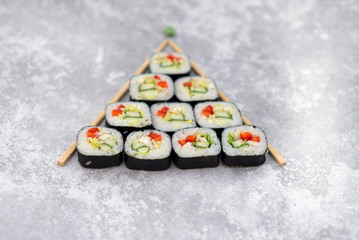 christmas tree made of sushi rolls on grey background 