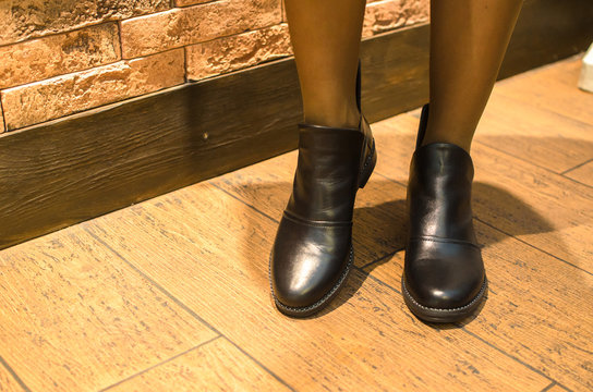 Girl in fashionable black shoes in a cafe on a wooden floor, illustrative photo