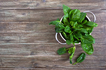 Fresh spinach leaves in a bowl on a wooden table. Useful, tasty, low-calorie greens. Young spinach...