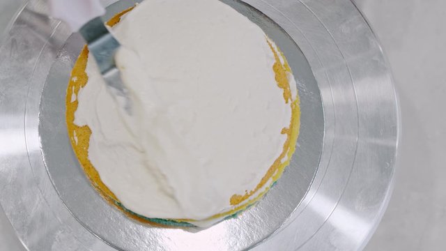 Icing a cake with whipped cream and a spatula