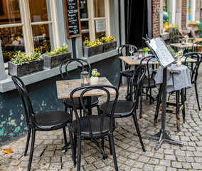 Fototapeta na wymiar Selective focus on outdoor dining tables and chairs on the street outside a Dutch cafe in the town of Maastricht