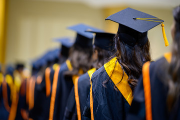 The back of the graduates are walking to attend the graduation ceremony at the university