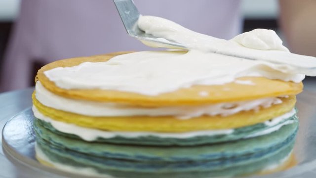 Scooping whipped cream on to colored cake layers