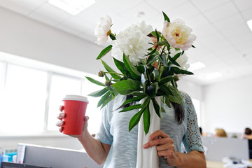 man holding a bouquet of peonies of flowers and a glass of coffee