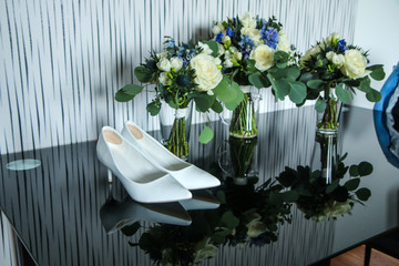 The picture of the equipment for the bride for the wedding. The bouquets of roses standing on the table together with the shoes. 