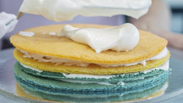 Scooping whipped cream on to colored cake layers