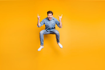 Full length body size photo of cheerufl shouting guy with fingers horned wearing sneakers showing rock horned fingers sign jumping isolated vivid color background