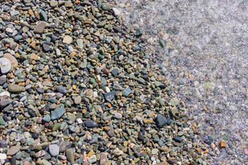pebble coastline. Seashore  with transparent water and small stones