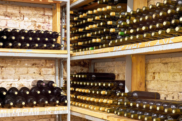 Horizontal rows of wine bottles on the shelf in a cellar. With the inscription in Russian 