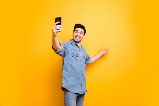 Photo of trendy white cheerful man taking selfie recording video demonstrating empty space behind inviting viewers to come isolated vivid color background