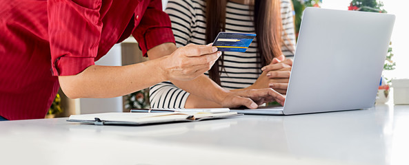 Online Payment. Happy asian woman holding smartphone and using credit card for online shopping with christmas tree and christmas decoration.