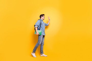 Fototapeta na wymiar Full length body size profile side view of his he nice attractive cheerful cheery friendly guy walking waving meeting buddy isolated over bright vivid shine vibrant yellow color background