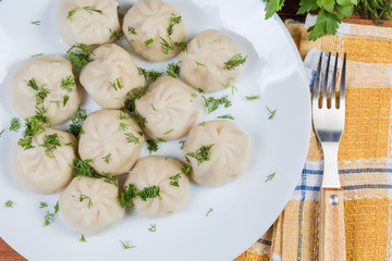 Boiled khinkali with chopped dill on dish, fragment top view