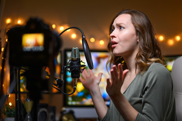 Actively, the girl talks to her viewers on a video camera. Record of vlogs, YouTube, live stream,...