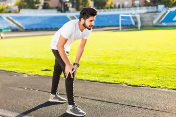 Indian young muscular athlete is at the start of the treadmill at the stadium