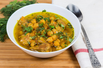 Stewed chickpeas with meat and vegetables in bowl close-up