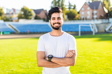 Confident sportsman blue sport clothing stadium background. Athlete confident holds hands crossed. Man athlete muscular arms ready for training outdoors.