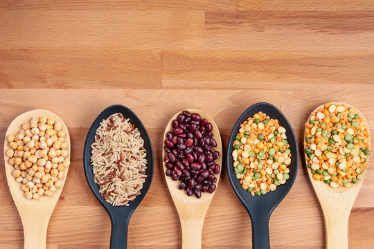 Bean grains in tablespoons on a wooden background. Natural healthy eating concept