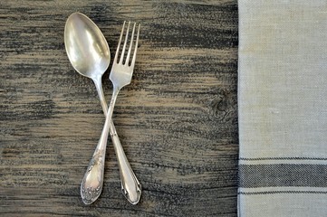 Old fork with spoon and towel on wooden background close up