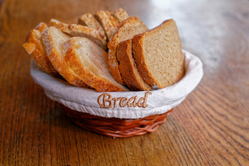 Basket of white, wholegrain and wholegrain bread slices on a wooden table under natural daylight. Bread text written on the basket.