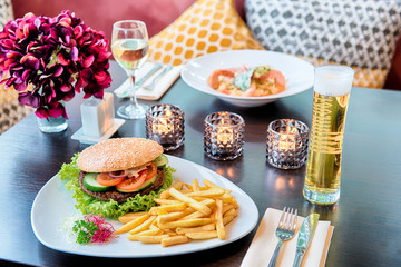 Burger mit Pommes und Bier auf einem Tisch