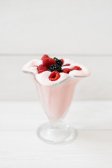 Milk raspberry cocktail with fresh raspberries and blackberries in a glass on a white background