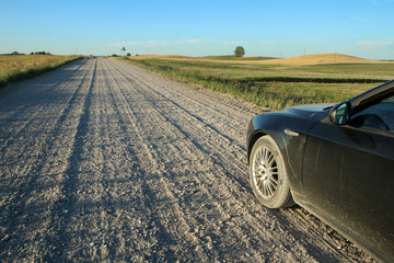 The picture from the Lithuaunian countryside taken in the nice summer showing the gravel road and the countryside. 