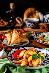 The concept of Uzbek cuisine. Different oriental dishes on the table in national Uzbek plates. Rustic fried potatoes. background image. copy space