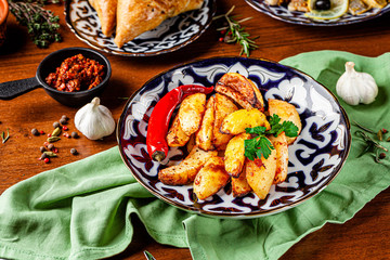 The concept of Uzbek cuisine. Different oriental dishes on the table in national Uzbek plates. Rustic fried potatoes. background image. copy space