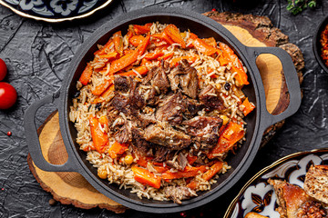 The concept of Uzbek cuisine. Eastern pilaf in a cast-iron pan. background image. copy space. top...