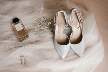 Bride's accessories: shoes, eau de toilette or perfume, earrings and a sprig of gypsophila flowers...