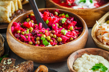 Beetroot salad vinaigrette with carrots, peas, sauerkraut in wooden bowl. Traditional Russian cuisine concept.