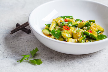 Asian smashed cucumber salad with chili and sesame seeds in white bowl. Chinese food concept.