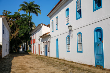 Typical cobblestone street covered with mud from high tide with colonial buildings on a sunny day in historic town Paraty, Brazil