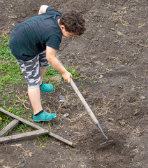 The boy works with the land in the garden