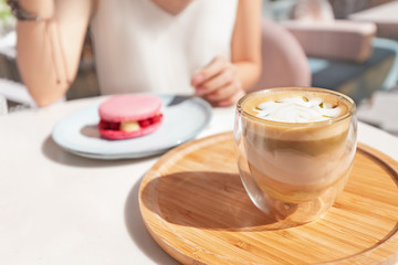eating sweet pink macaroon with raspberries and drinking delicious pistachio coffee in a French cafe