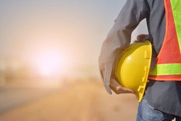 Close up Engineering holding Yellow helmet hard hat safety and Road construction background