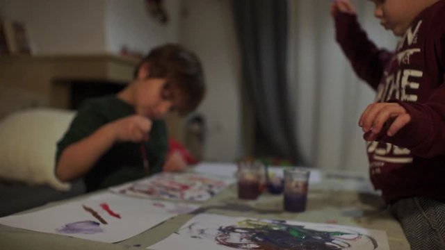 Caucasian toddlers paint watercolours on a table indoors 