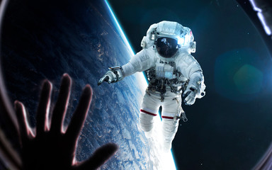 Woman looks at astronaut through the spaceship porthole. Elements of this image furnished by NASA